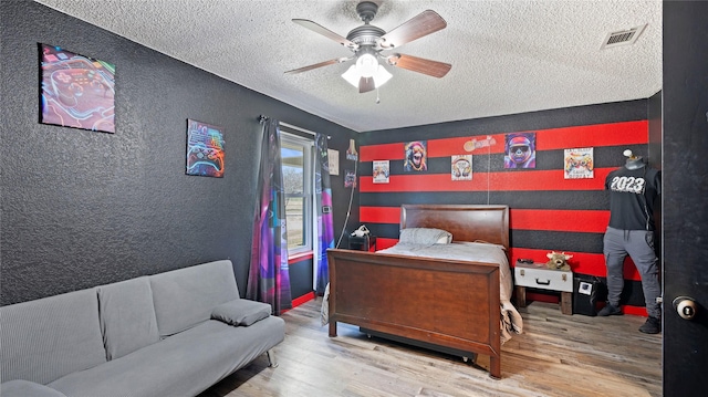 bedroom with ceiling fan, a textured ceiling, and hardwood / wood-style flooring