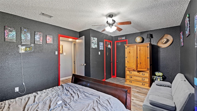 bedroom with ceiling fan, wood-type flooring, and a textured ceiling