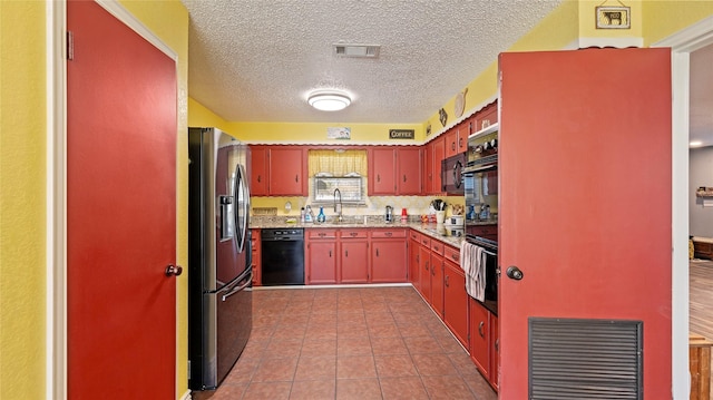 kitchen featuring sink, light tile patterned floors, black appliances, and a textured ceiling