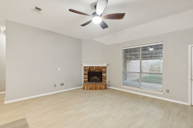 unfurnished living room with vaulted ceiling, a brick fireplace, ceiling fan, and light hardwood / wood-style floors