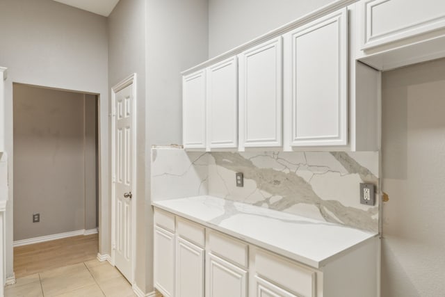 kitchen with white cabinetry, light tile patterned floors, decorative backsplash, and light stone countertops