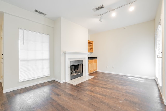 unfurnished living room with rail lighting, a fireplace, and dark wood-type flooring