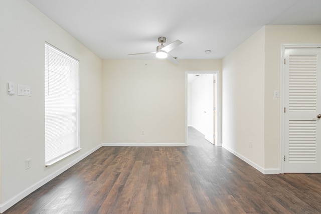 empty room with a healthy amount of sunlight, ceiling fan, and dark wood-type flooring