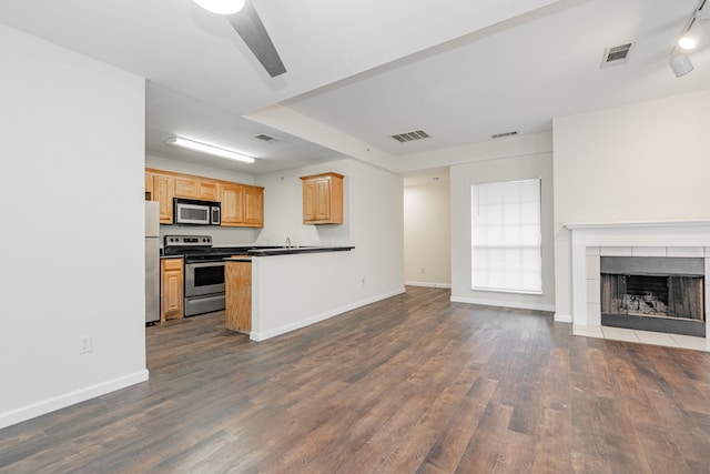 kitchen featuring a tiled fireplace, kitchen peninsula, stainless steel appliances, and dark wood-type flooring