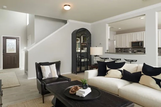 living room with light hardwood / wood-style floors, sink, and crown molding