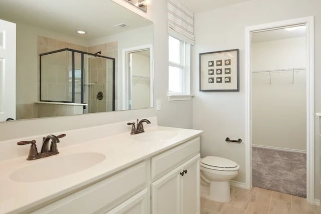 bathroom featuring a shower with door, vanity, and toilet