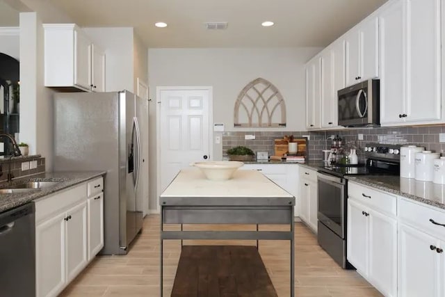 kitchen with white cabinets, dark stone countertops, sink, and stainless steel appliances