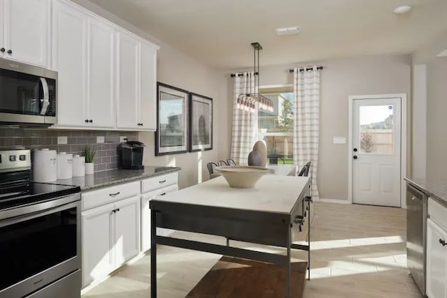 kitchen featuring pendant lighting, white cabinets, and appliances with stainless steel finishes