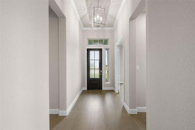 foyer with a chandelier, hardwood / wood-style flooring, and crown molding