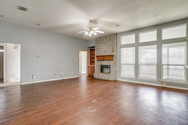 unfurnished living room featuring ceiling fan, wood-type flooring, and a fireplace