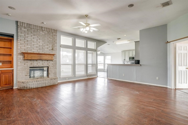 unfurnished living room with hardwood / wood-style floors, a textured ceiling, and a brick fireplace