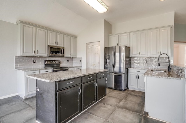 kitchen with decorative backsplash, stainless steel appliances, sink, a kitchen island, and lofted ceiling