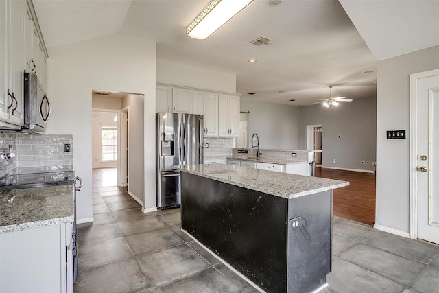 kitchen featuring a center island, lofted ceiling, backsplash, and appliances with stainless steel finishes