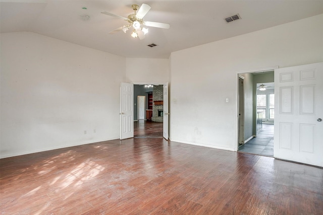 empty room with ceiling fan, dark hardwood / wood-style flooring, lofted ceiling, and a brick fireplace