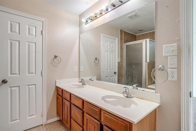 bathroom with tile patterned flooring, vanity, an enclosed shower, and a textured ceiling