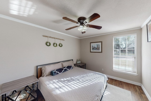 bedroom with ceiling fan, a textured ceiling, ornamental molding, and hardwood / wood-style floors