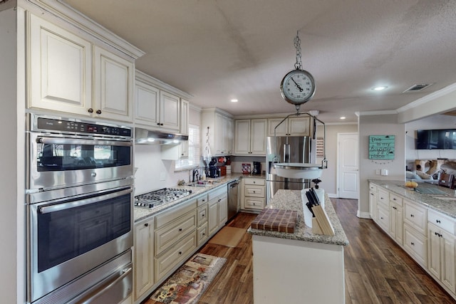 kitchen with decorative light fixtures, a center island, stainless steel appliances, dark hardwood / wood-style flooring, and light stone counters