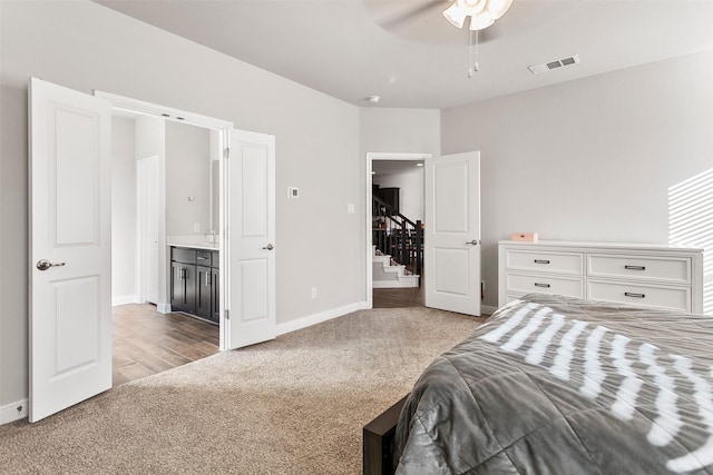 bedroom with light colored carpet, ceiling fan, and ensuite bathroom