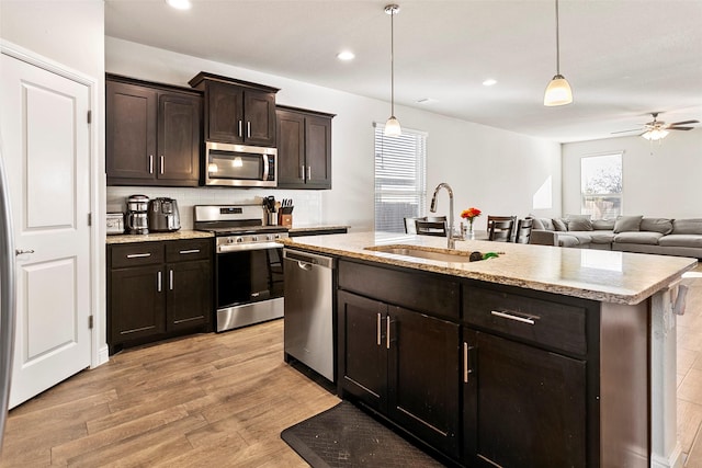 kitchen with sink, stainless steel appliances, an island with sink, light hardwood / wood-style floors, and dark brown cabinets