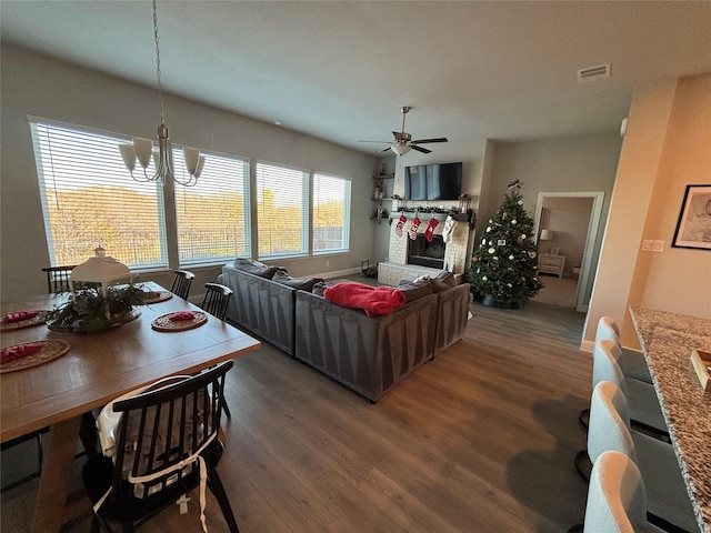 living room featuring ceiling fan with notable chandelier and dark wood-type flooring