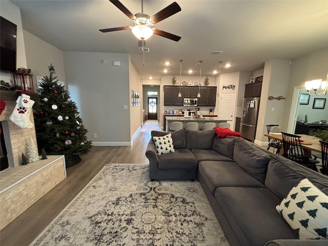 living room featuring ceiling fan with notable chandelier and wood-type flooring