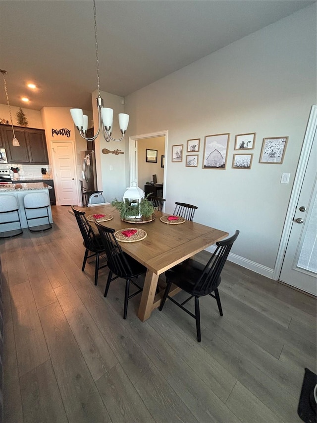 dining area featuring dark wood-type flooring and an inviting chandelier