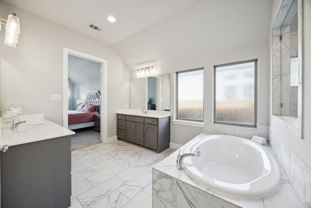 bathroom featuring a relaxing tiled tub, lofted ceiling, and vanity