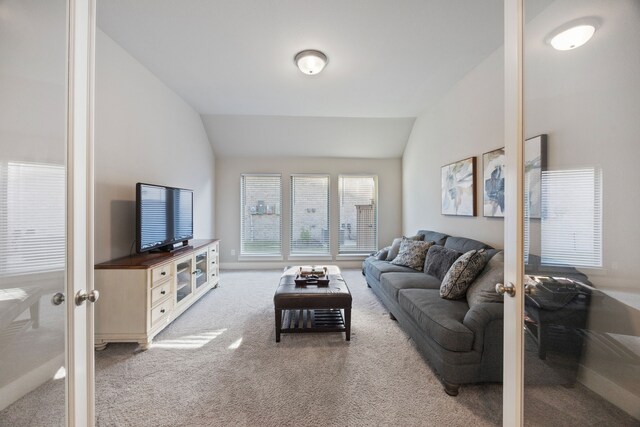 carpeted living room with french doors and vaulted ceiling