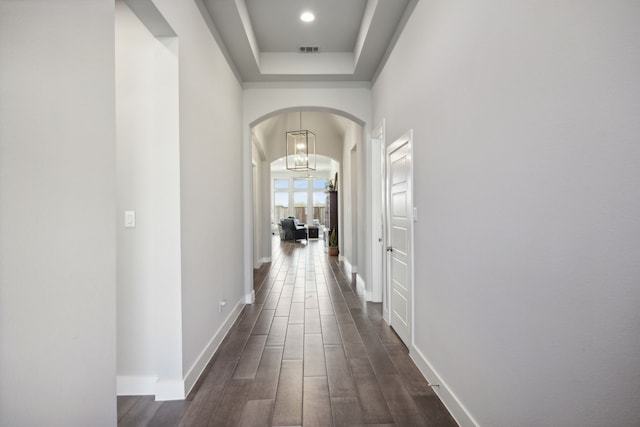 hallway with dark wood-type flooring and a chandelier