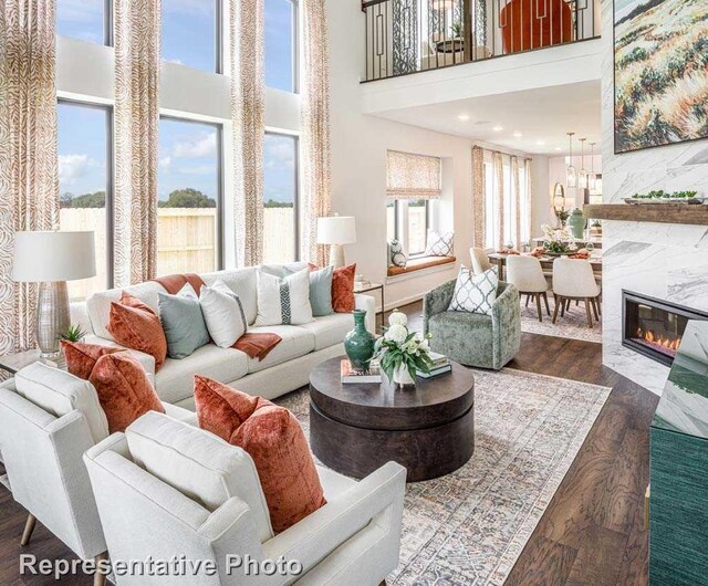 living room with a tile fireplace, a towering ceiling, and dark wood-type flooring