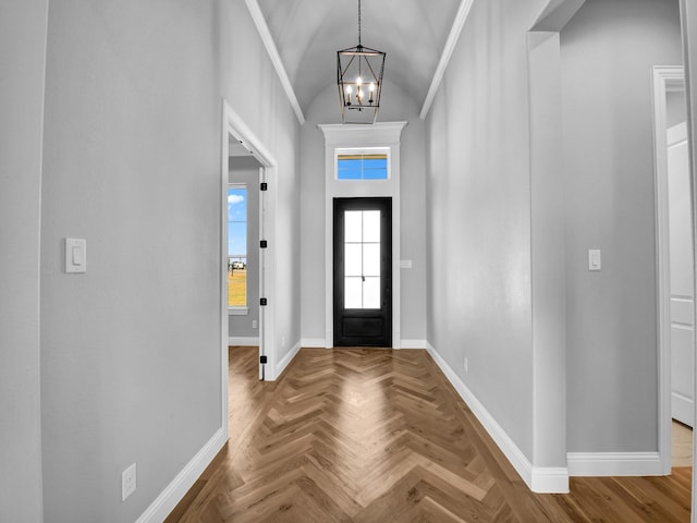 foyer with parquet flooring, lofted ceiling, an inviting chandelier, and crown molding