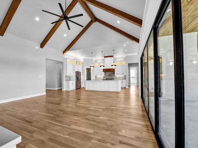 unfurnished living room with ceiling fan, beam ceiling, high vaulted ceiling, and light hardwood / wood-style flooring