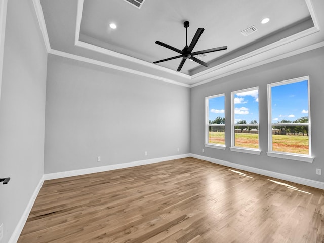 unfurnished room featuring a tray ceiling, hardwood / wood-style flooring, and ornamental molding