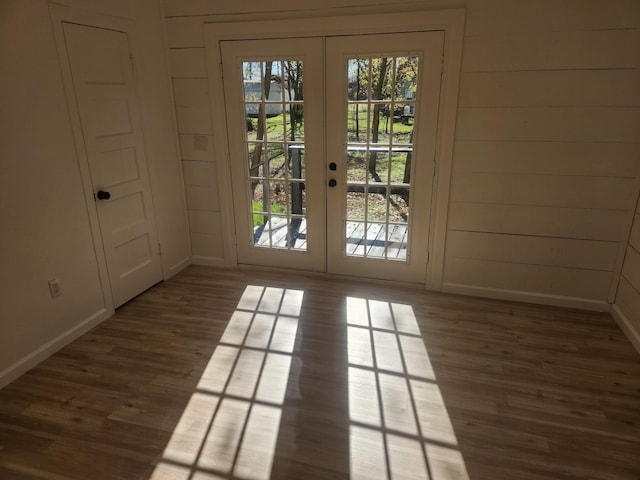 doorway to outside featuring dark hardwood / wood-style flooring, wooden walls, and french doors