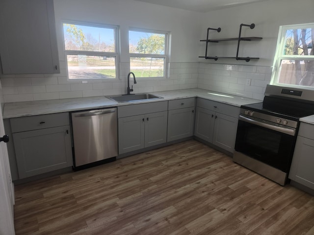 kitchen with appliances with stainless steel finishes, gray cabinets, dark hardwood / wood-style floors, and sink