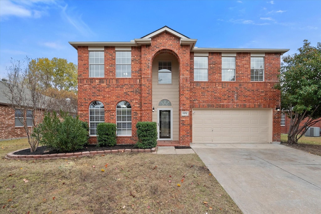 view of front of house with central AC unit, a garage, and a front lawn