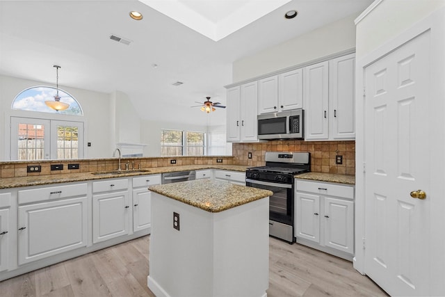 kitchen featuring white cabinetry, sink, hanging light fixtures, light stone counters, and stainless steel appliances