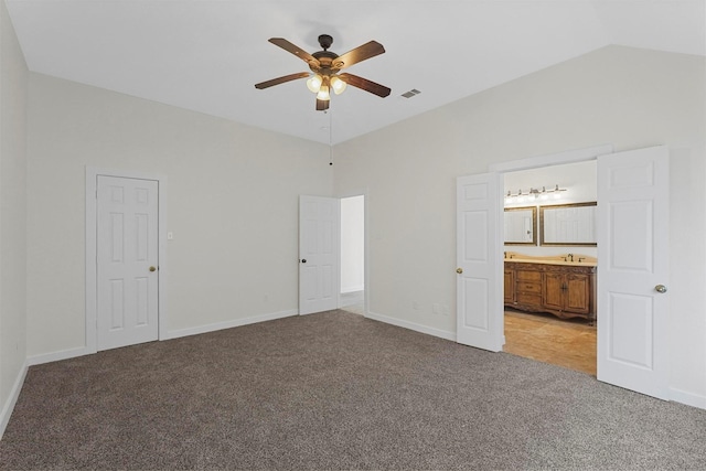 unfurnished bedroom featuring sink, ceiling fan, carpet, connected bathroom, and vaulted ceiling