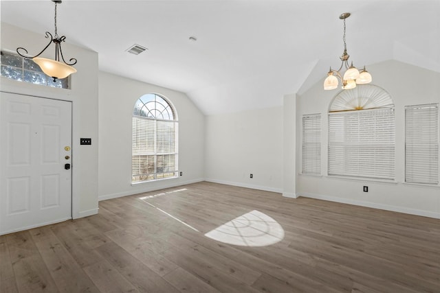 entryway featuring hardwood / wood-style flooring, vaulted ceiling, and a chandelier