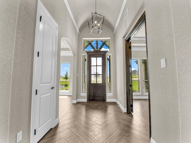 foyer entrance featuring crown molding, parquet floors, a chandelier, and lofted ceiling