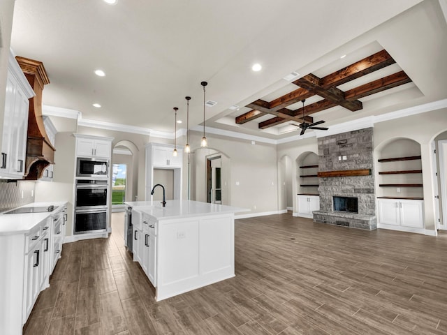 kitchen with decorative light fixtures, dark hardwood / wood-style flooring, white cabinetry, and a kitchen island with sink