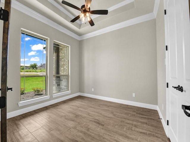 unfurnished room featuring a raised ceiling, ceiling fan, wood-type flooring, and ornamental molding