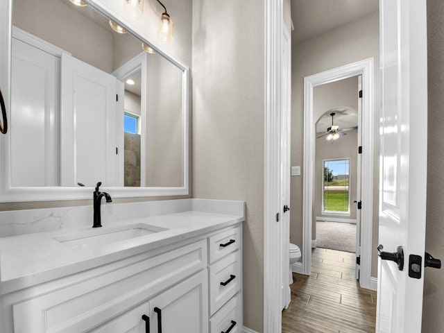 bathroom featuring ceiling fan, toilet, vanity, and hardwood / wood-style flooring