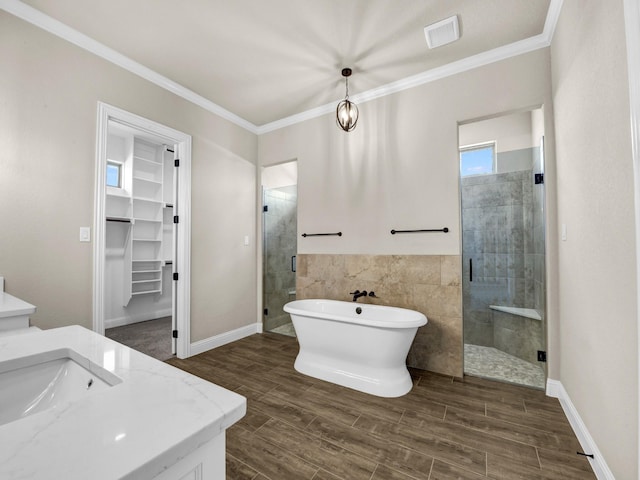 bathroom featuring crown molding, vanity, hardwood / wood-style flooring, and shower with separate bathtub