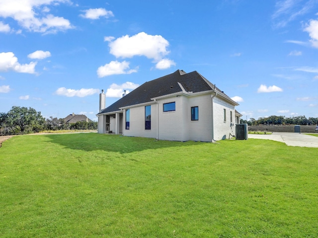 rear view of property featuring a lawn and central AC unit