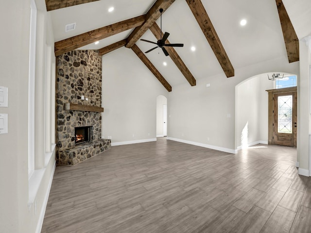 unfurnished living room with hardwood / wood-style flooring, a stone fireplace, and beamed ceiling