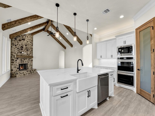 kitchen featuring a kitchen island with sink, vaulted ceiling with beams, ceiling fan, white cabinetry, and stainless steel appliances