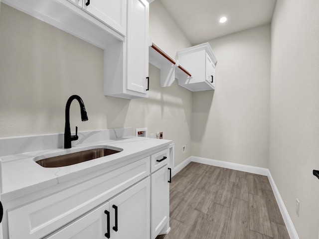 laundry area featuring cabinets, hookup for a washing machine, electric dryer hookup, sink, and light hardwood / wood-style floors