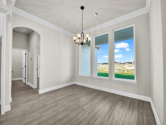 spare room with light wood-type flooring, crown molding, and an inviting chandelier