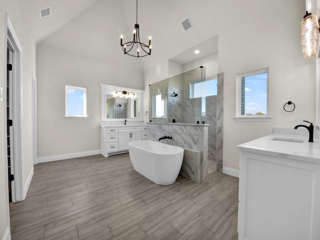 bathroom featuring vanity, an inviting chandelier, vaulted ceiling, hardwood / wood-style flooring, and separate shower and tub